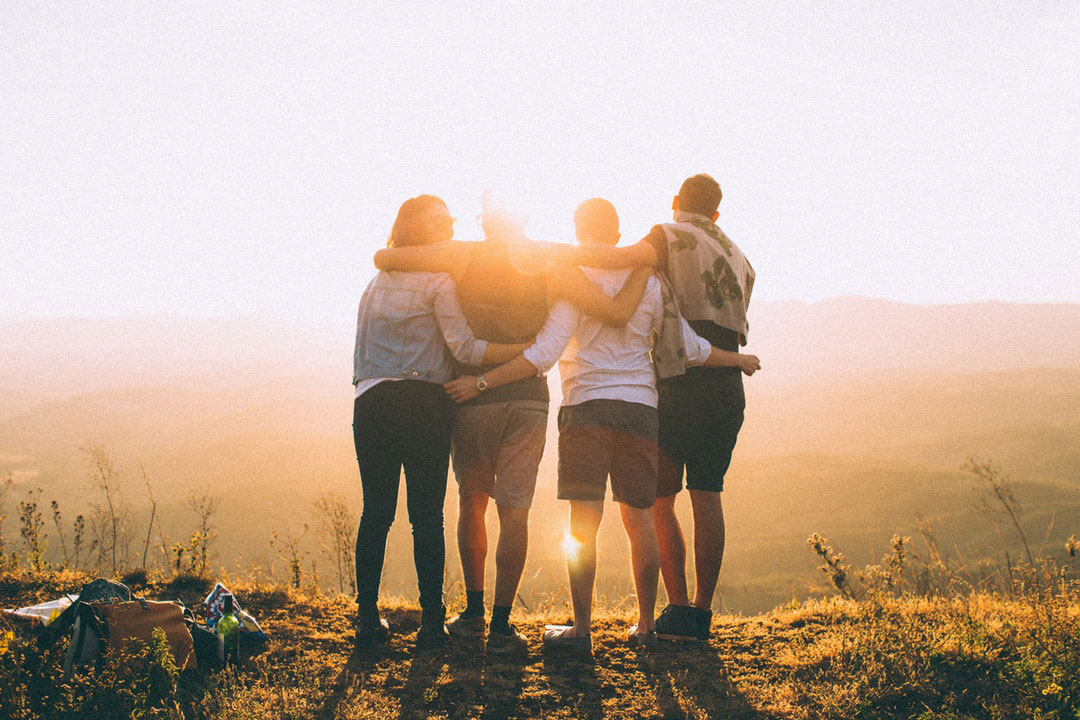 Teamwork photograph of four friends at the summit of a high peak